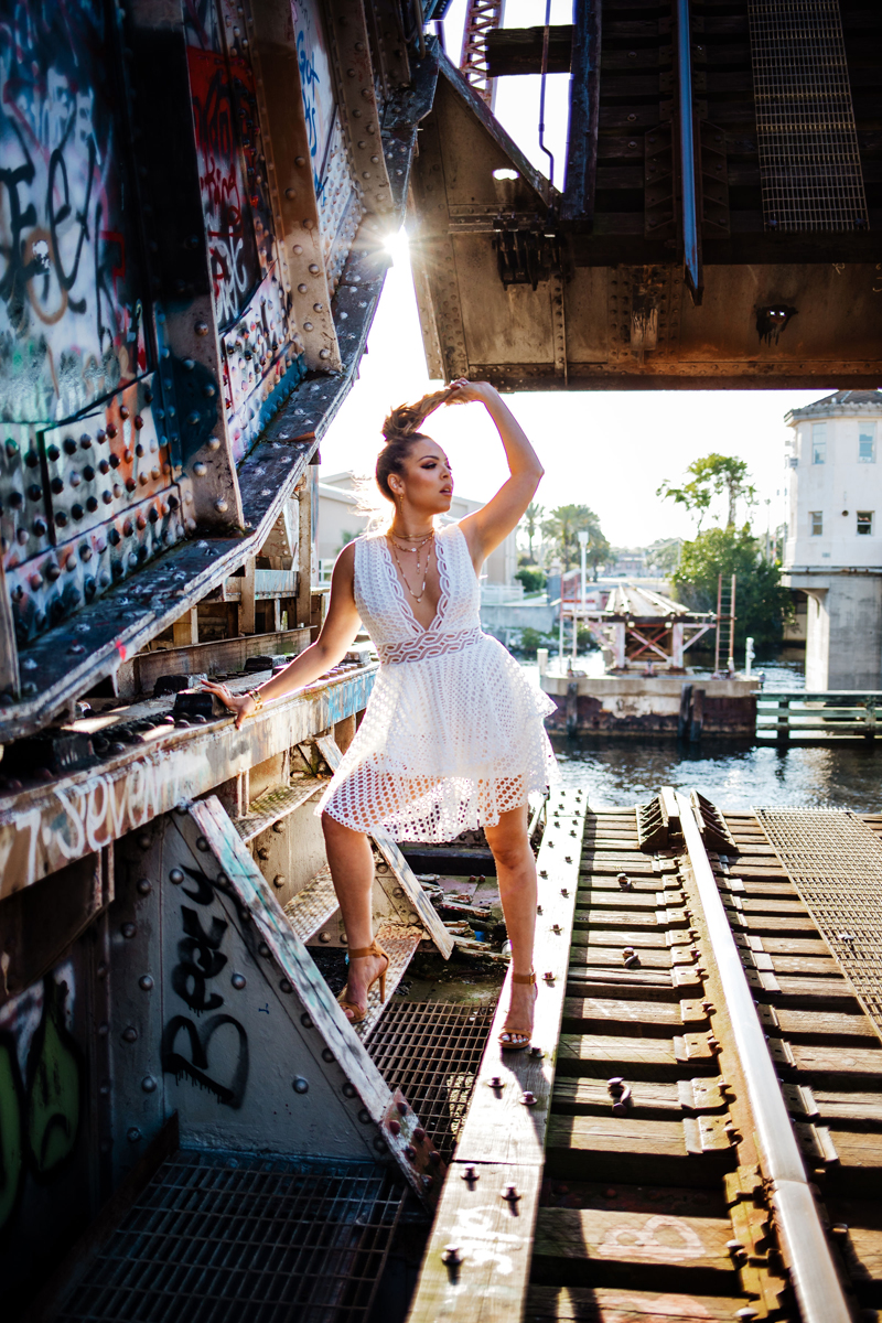 Atlanta Blogger-Influencer Photographer, a woman in a lacy white dress stands beside a toll bridge covered in graffiti