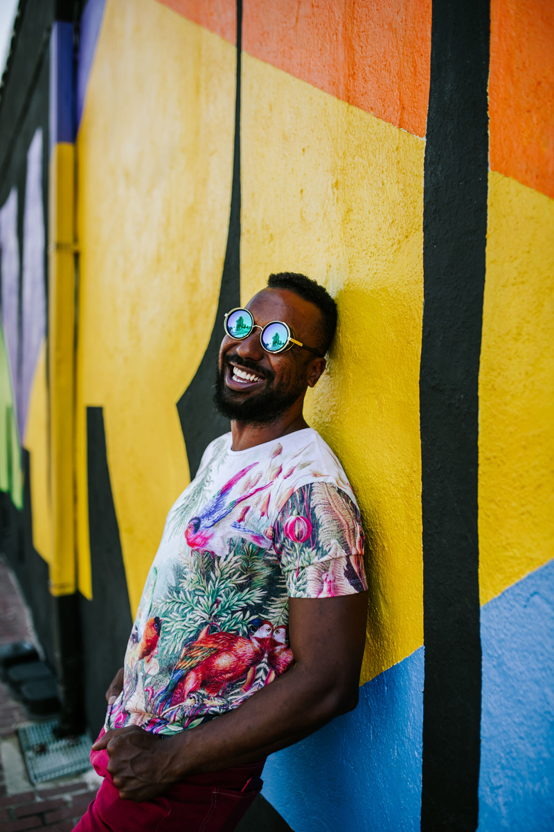 Atlanta Influencer-Blogger Photographer, man leans against colorful wall smiling