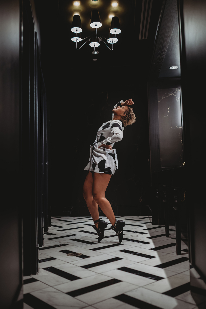 Atlanta Blogger-Influencer Photographer, a woman wears a black and white jumper while jumping over a black and white floor