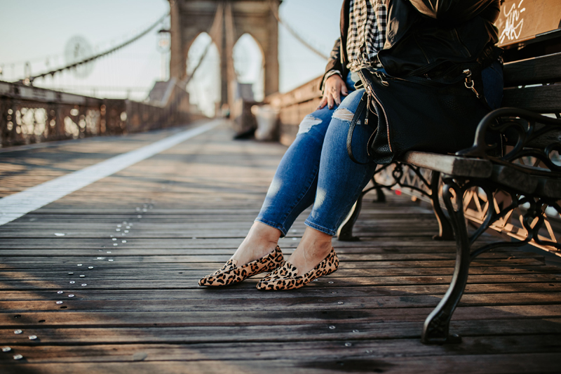 Atlanta Blogger-Influencer Photographer, a woman sits in a bench at the cable bridge wearing leopard slip-on shoes