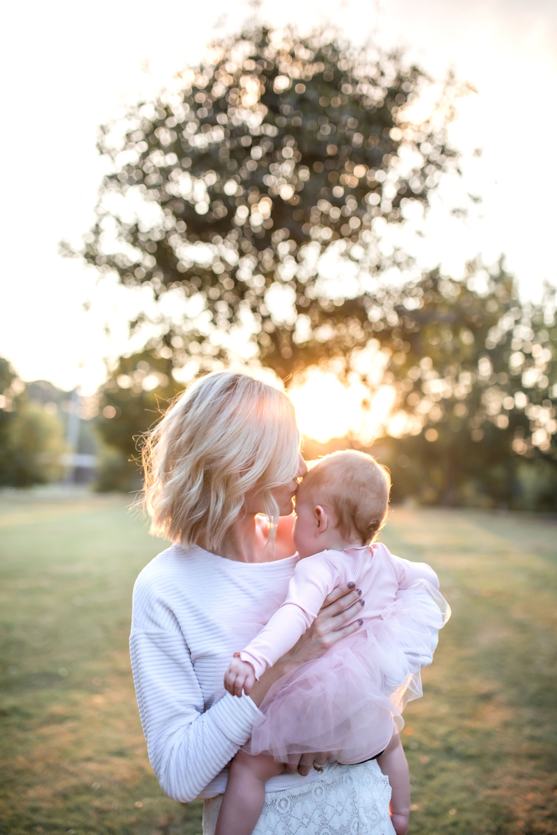 Atlanta Blogger-Influencer Photographer, Mother holds baby daughter with sun shining brightly behind her