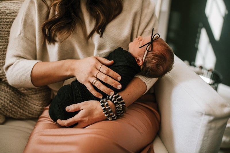 Atlanta Newborn Photographer, mother holds newborn baby closely on lap