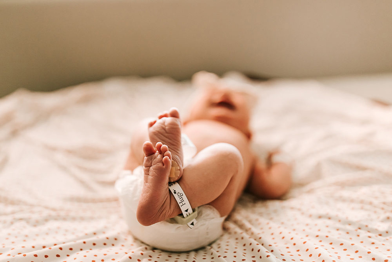 Atlanta Newborn Photographer, baby lays in hospital bed with tiny feet perched up in air