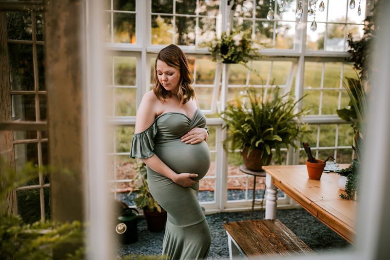 Atlanta Maternity Photographer, full term pregnant woman in green dress stands in greenhouse