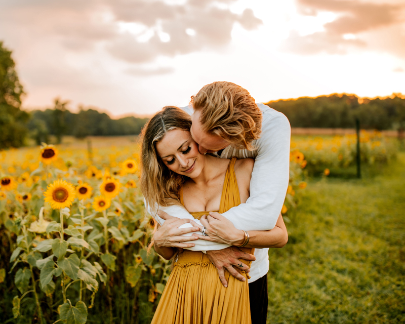 Atlanta Couples Photographer, man embracing woman in front of sunflower field