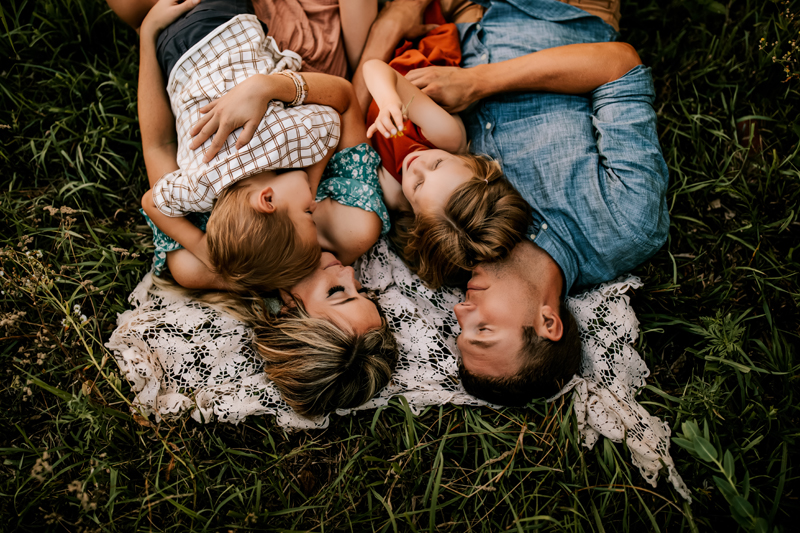 Atlanta Family Photographer, mother and father hold son and daughter as they lay on a blanket in the grass