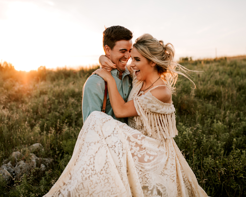 Atlanta Couples Photographer, Laughing together, a man lifts up his wife in a grassy field