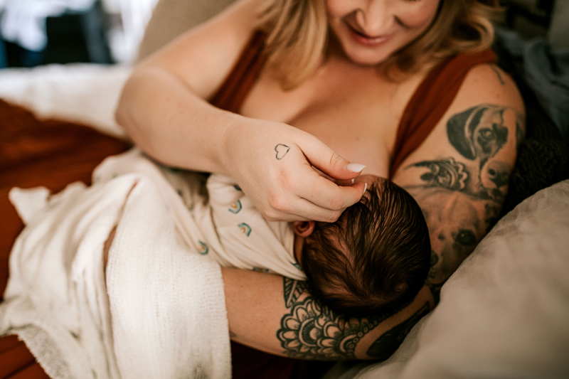 Atlanta Newborn Photographer, woman breastfeeds a newborn baby, she holds baby with her tattooed arm