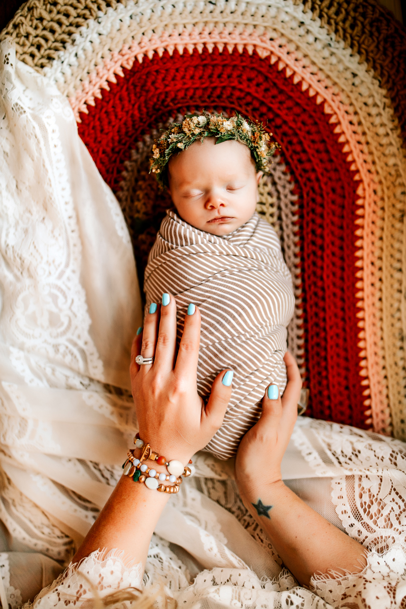 Atlanta Newborn Photographer, baby wrapped in blanket asleep wearing a floral crown, moms hands holding her
